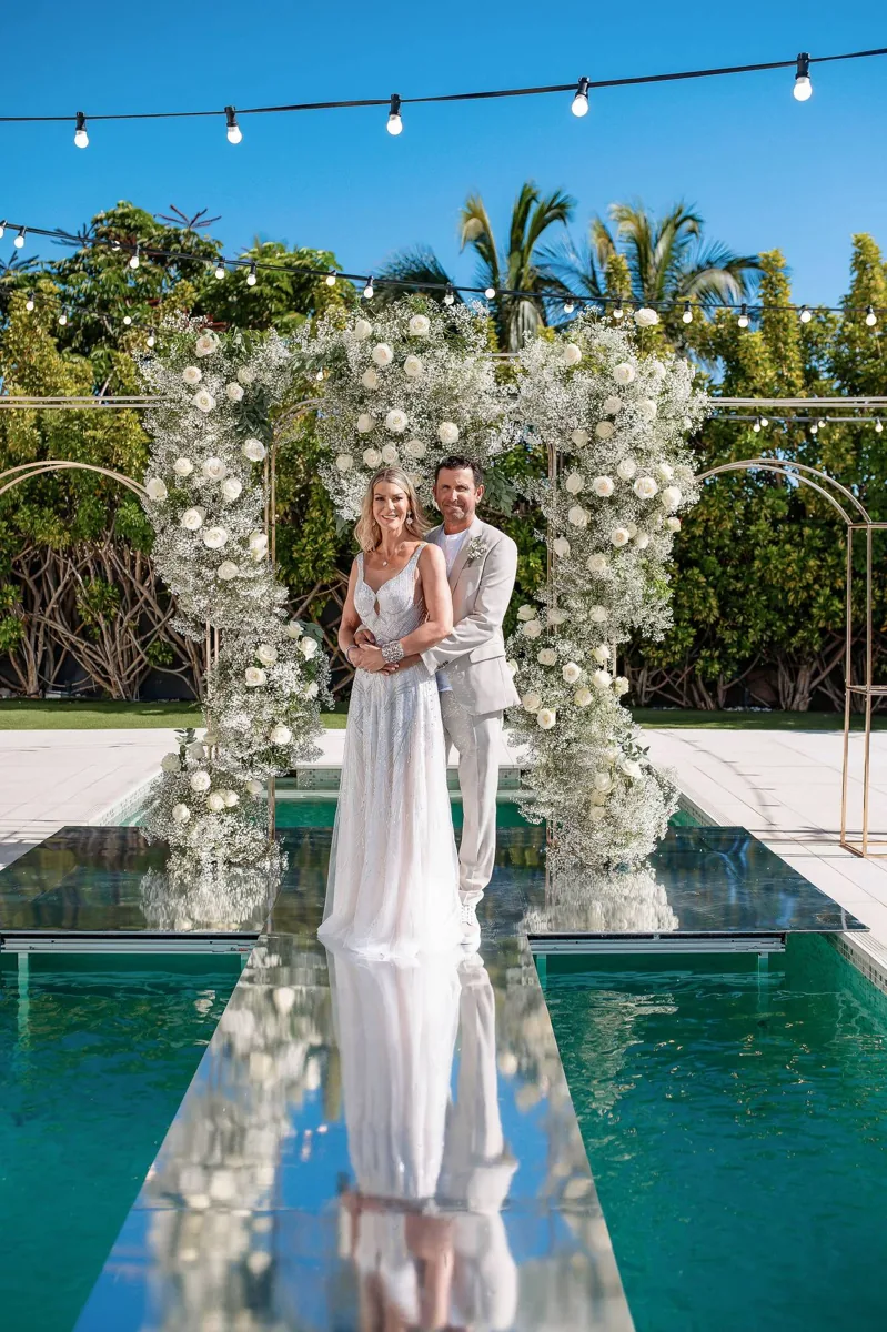 Couple beneath a white floral arch reflected in the pool at Casa Amore Tenerife